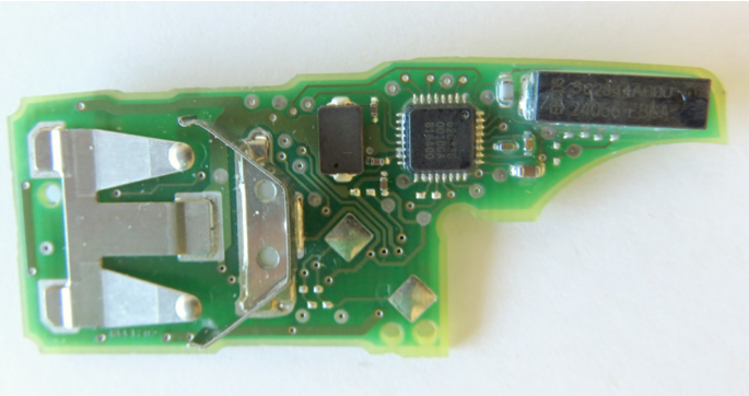 PCB of a newer-generation VW Group remote control carrying the unidentified microcontroller used across the VW3 and VW4 schemes; firmware extraction was complicated by the obscure markings and undocumented programming interface. Figure from Garcia et al., 2016 (Lock It and Still Lose It).